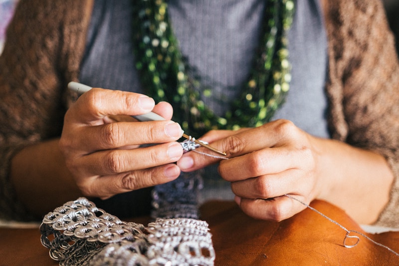 A woman holding a crochet hook and yarn