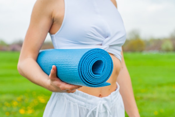 Woman holding rolled up yoga mat