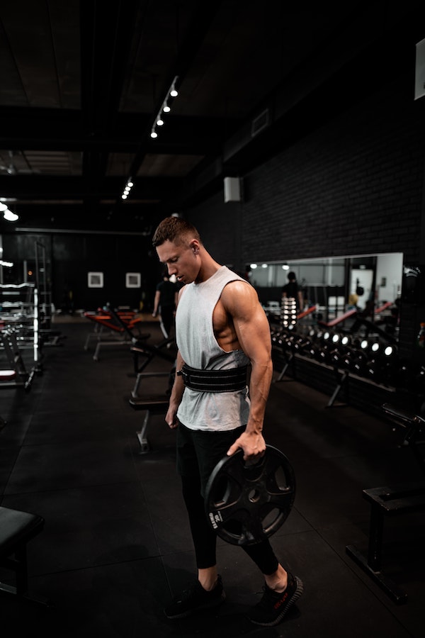 Guy holding weights in a tank top at the gym