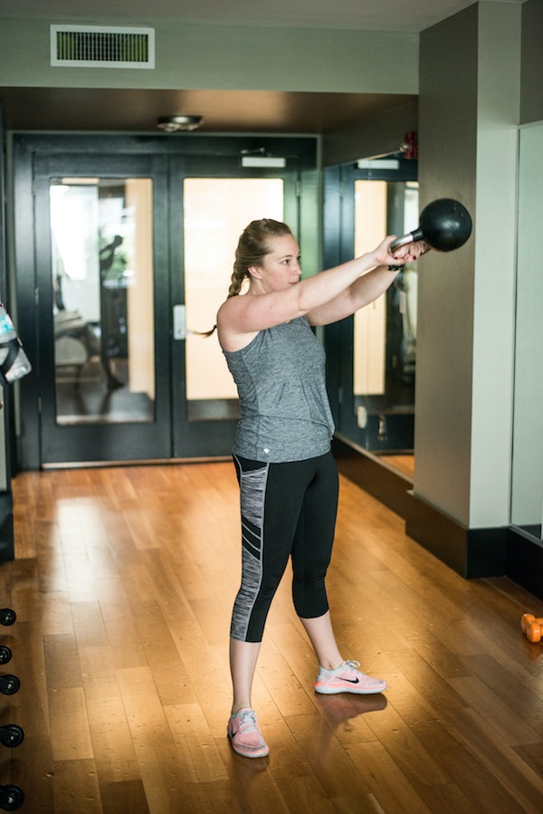 Woman doing kettlebell swing in gym