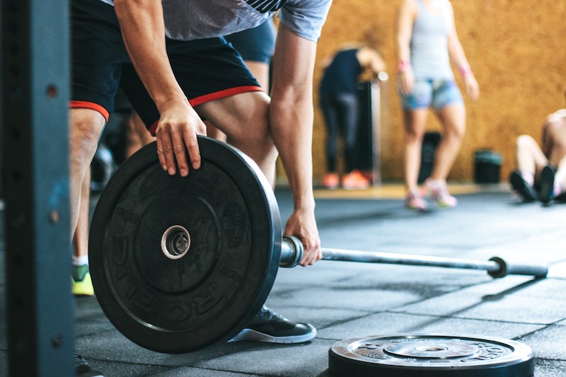 Man loading olympic plates onto barbell