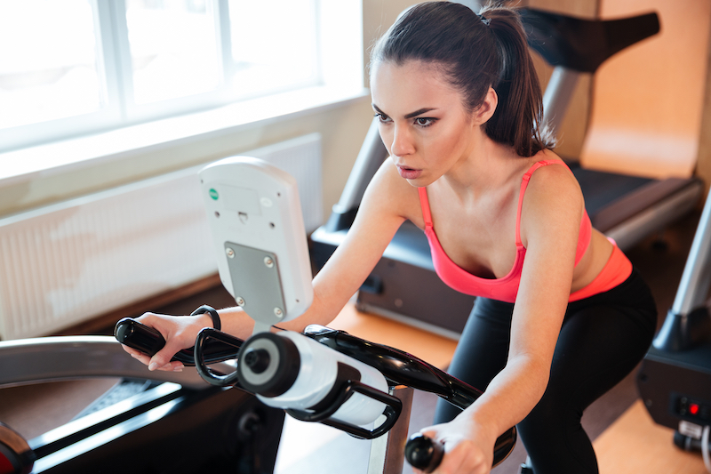 Woman riding stationary spin bike at the gym