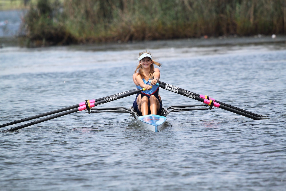 A female crew team rowing on the water